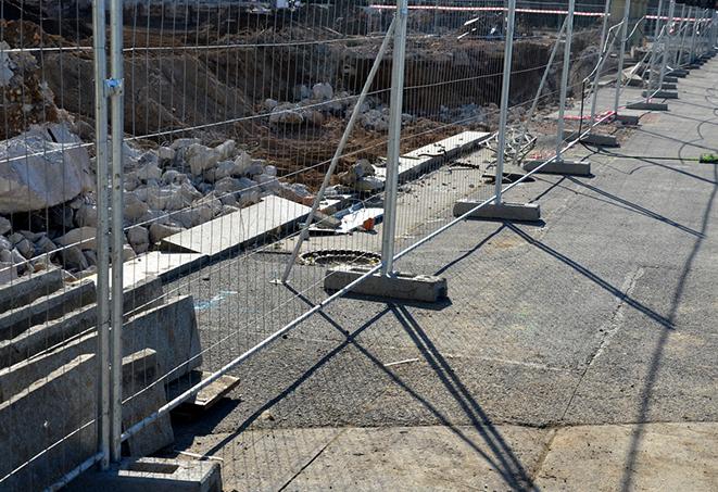 construction workers installing temporary fence panels for a construction site perimeter